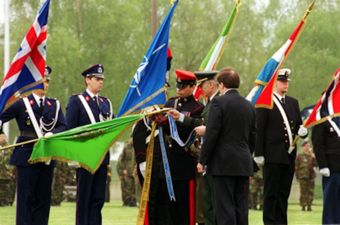 Supreme Allied Commander Europe Gen. Wesley K. Clark (center), U.S. Army, attaches the Joint Meritorious Unit Award to the unit colors during his change of command ceremony in Mons, Belgium, on May 3, 2000. Accompanying Clark on the field is NATO Secretary General Lord George Robertson (right). Clark relinquished command to Gen. Joseph W. Ralston, U.S. Air Force. 
