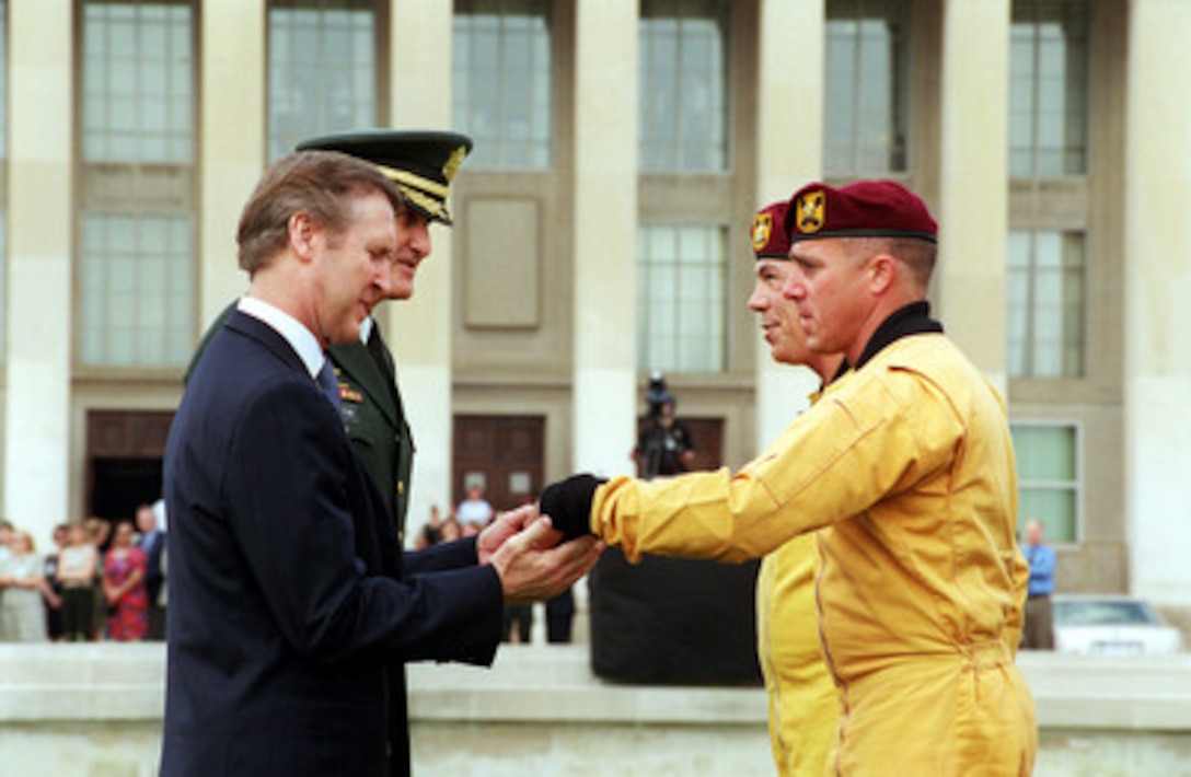 Secretary of Defense William S. Cohen and Chairman of the Joint Chiefs of Staff Gen. Henry H. Shelton, U.S. Army, receive batons from members of the U.S. Army's Golden Knights Parachute Team at the Pentagon on May 18, 2000. The precision parachutists landed on the Pentagon Parade Field at the conclusion of the 50th Anniversary Armed Forces Day ceremony. Cohen and Shelton co-hosted the event which honored approximately 300 "unsung heroes" who are military and civilian employees of the Department of Defense in the National Capital region. 