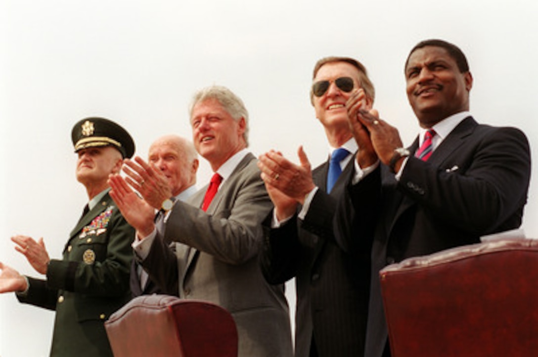 President Bill Clinton (center) leads the applause for a fly-by of aircraft from each of the five armed services during the opening ceremonies of the annual joint services open house and air show at Andrews Air Force Base, Md., on May 19, 2000. This year's event commemorates the 50th anniversary of Armed Forces Day. Joining Clinton on the platform are from left to right: Chairman of the Joint Chiefs of Staff Gen. Henry H. Shelton, U.S. Army; Sen. John Glenn (D-Ohio); Secretary of Defense William S. Cohen and Secretary of Transportation Rodney E. Slater. 