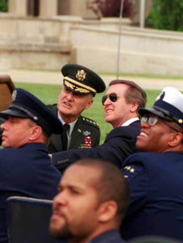 Chairman of the Joint Chiefs of Staff Gen. Henry H. Shelton (top left), U.S. Army, and Secretary of Defense William S. Cohen (top right) watch the sky as jumpers of the U.S. Army's Golden Knights Parachute Team descend towards the center of the Pentagon Parade Field on May 18, 2000. The precision parachutists landed on the Pentagon Parade Field at the conclusion of the 50th Anniversary Armed Forces Day ceremony. Cohen and Shelton co-hosted the event which honored approximately 300 "unsung heroes" who are military and civilian employees of the Department of Defense in the National Capital region. 