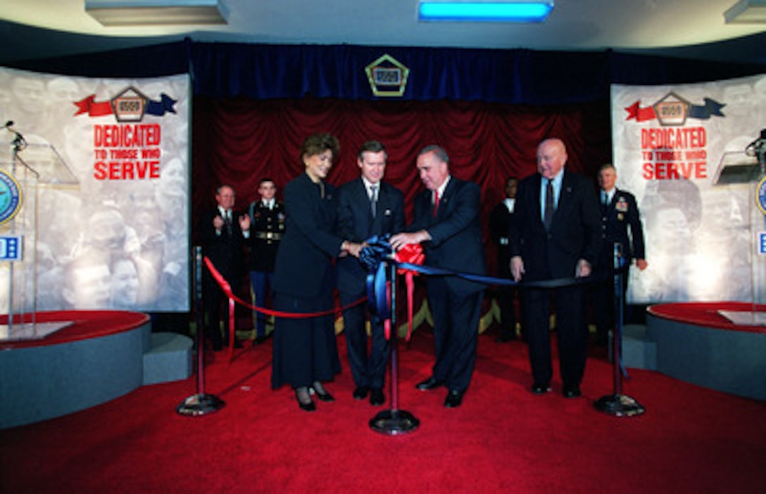 Janet Langhart Cohen (left), Secretary of Defense William S. Cohen, retired Gen. John Tilelli, president of the United Service Organizations, and David O. "Doc" Cooke, director of Budget and Administration, join two ribbons at a ceremony marking the opening of the USO Corridor in the Pentagon on Nov. 2, 2000. The display commemorates the close relationship between the Department of Defense and the USO. 