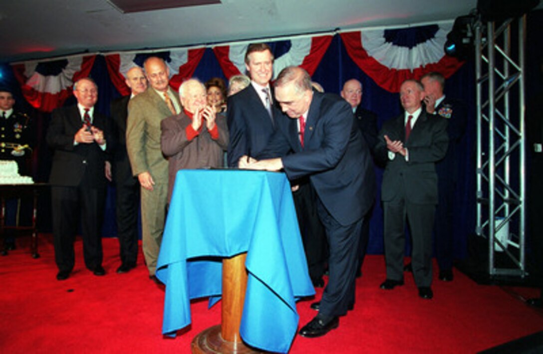 Surrounded by celebrities and officials, retired Gen. John Tilelli, president of the United Service Organizations, signs a proclamation with the Department of Defense as Secretary of Defense William S. Cohen (left) looks on and USO entertainer Mickey Rooney applauds in ceremony at the Pentagon on Nov. 2, 2000. The ceremony marked the opening of the display commemorating the close relationship of the two organizations in the new USO Corridor of the Pentagon. 