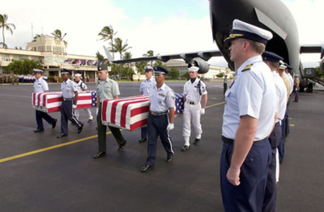 Two joint service honor guards remove flag-draped transfer cases containing remains believed to be those of Americans lost during the wars in Korea and Vietnam from an Air Force C-17 Globemaster III during a ceremony at Hickam Air Force Base, Hawaii, on Nov. 20, 2000. Twenty-one sets of remains were repatriated to American soil during the ceremony. The repatriated remains will go to the U.S. Army's Central Identification Laboratory in Hawaii for forensic identification. 