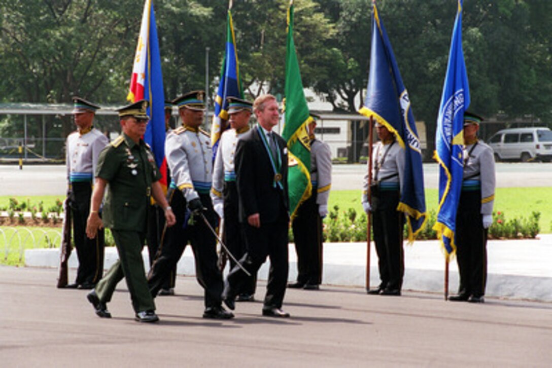 Secretary of Defense William S. Cohen (right) wears the Medallion of the Armed Forces General Headquarters of Philippines as he inspects the troops at Camp Aguinaldo on Sept. 15, 2000. Chief of Staff of the Armed Forces of the Philippines General Angelo T. Reyes (left) hosted the armed forces welcoming ceremony. 
