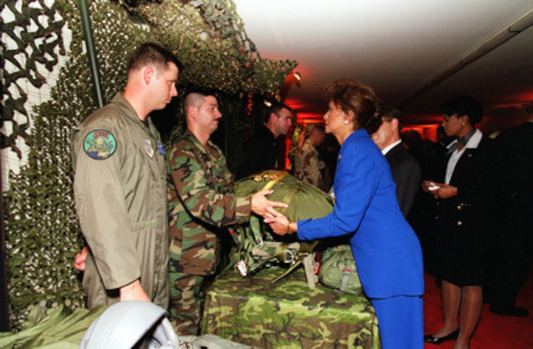Mrs. Janet Langhart Cohen (right) feels the heft of a parachute which is carried in addition to the photographic equipment used by combat cameramen in their mission. This static display was part of the Pentagon reception and film preview of the Dreamworks film on combat cameramen "Shooting War" on Oct. 4, 2000. Secretary of Defense and Mrs. Cohen invited 250 defense leaders, commanders and corporate executives to the Department of Defense tribute to the military's past and present combat cameramen. 