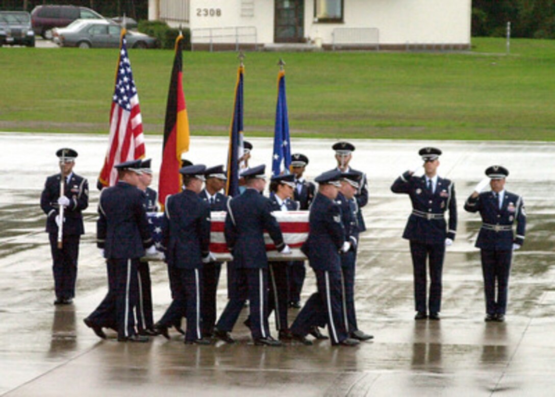A U.S. Air Force honor guard salutes as the remains of a sailor killed in the suspected terrorist attack on the USS Cole (DDG 67) are carried from a C-17 Globemaster III at Ramstein Air Base, Germany, on Oct. 13, 2000. The attack on the Arleigh Burke class destroyer took place in the Yemen port city of Aden on Oct. 12, 2000. 