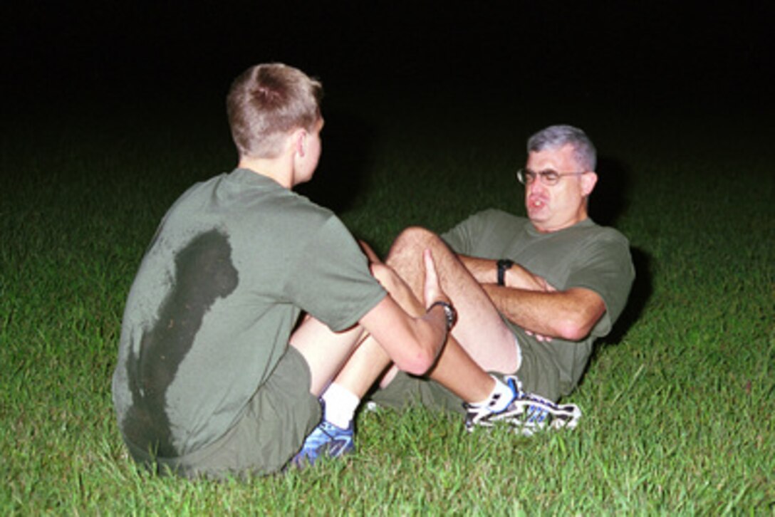 Richard Castanet (right) grunts through a sit-up as he and his son Christian do early physical training as part of their Marine Corps indoctrination at Marine Corps Base Quantico, Va., on Sept. 5, 2000. Castanet, from Richmond, Va., is the Marine winner of the Yahoo! Fantasy Careers in Today's Military Contest. Father and son are experiencing Marine Corps training together. 