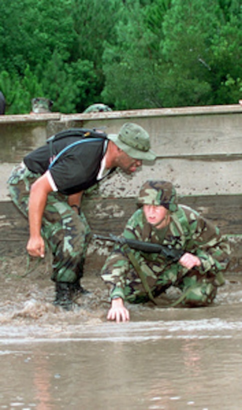 Sgt. Drake Ferguson (left) provides motivation to Christian Castanet as he negotiates a water hazard during training on the Individual Movement Course at Parris Island Recruit Training Depot, S.C., on Sept. 6, 2000. Castanet is the son of Richard A. Castanet, from Richmond, Va., who is the Marine winner of the Yahoo! Fantasy Careers in Today's Military Contest. Father and son are experiencing Marine Corps training together. 