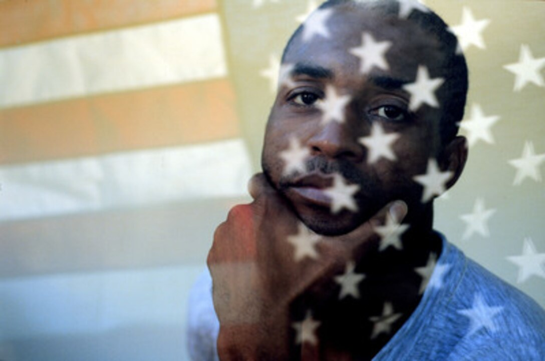 Navy Petty Officer 1st Class Steven Mays, team captain of the U.S. Olympic Greco-Roman wrestling team, looks through a window reflecting the U.S. flag at the 2000 Olympic Games in Sydney, Australia, on Sept. 14, 2000. Mays will wrestle in the 54 kg/119 lb. weight class. Fifteen U.S. military athletes are competing in the 2000 Olympic games as members of the U.S. Olympic team. In addition to the 15 competing athletes there are eight alternates and five coaches representing each of the four services in various venues. Mays is a Navy aviation boatswain's mate (Launch and Recovery Equipment) attached to the aircraft carrier USS John F. Kennedy (CV 67). 