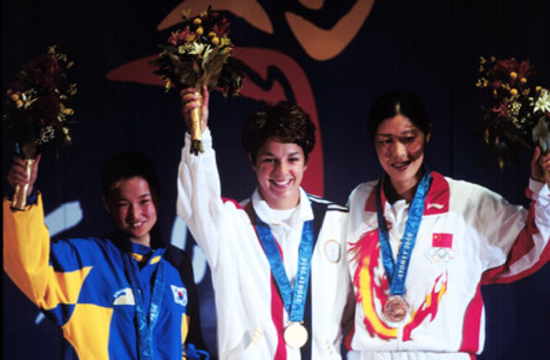 Gold medalist Nancy Johnson (center) of the U.S., raises her hands with silver medalist Cho-Hyun Kang (left), of Korea, and bronze winner Jing Gao (right), of China, during the medal ceremony for the women's 10 meter air rifle competition at the 2000 Olympic Games in Sydney, Australia, on Sept. 16, 2000. Johnson's gold medal is the first awarded in the Sydney Games and the first gold for the U.S. Johnson is married to U.S. Army Staff Sgt. Ken Johnson, who is also on the U.S. Olympic shooting team. 