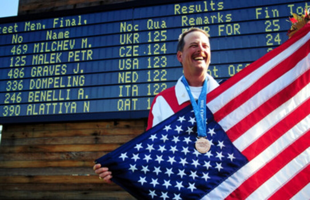 Sgt. 1st Class James T. Graves is all smiles as he holds the American flag up after winning the bronze medal in the Men's Skeet competition at the 2000 Olympic Games in Sydney, Australia, on Sept. 23, 2000. Graves is one of fifteen U.S. military athletes competing in the 2000 Olympic games as members of the U.S. Olympic team. In addition to the 15 competing athletes there are eight alternates and five coaches representing each of the four services in various venues. Graves is attached to the U.S. Army Marksmanship Unit, Fort Benning, Ga. 