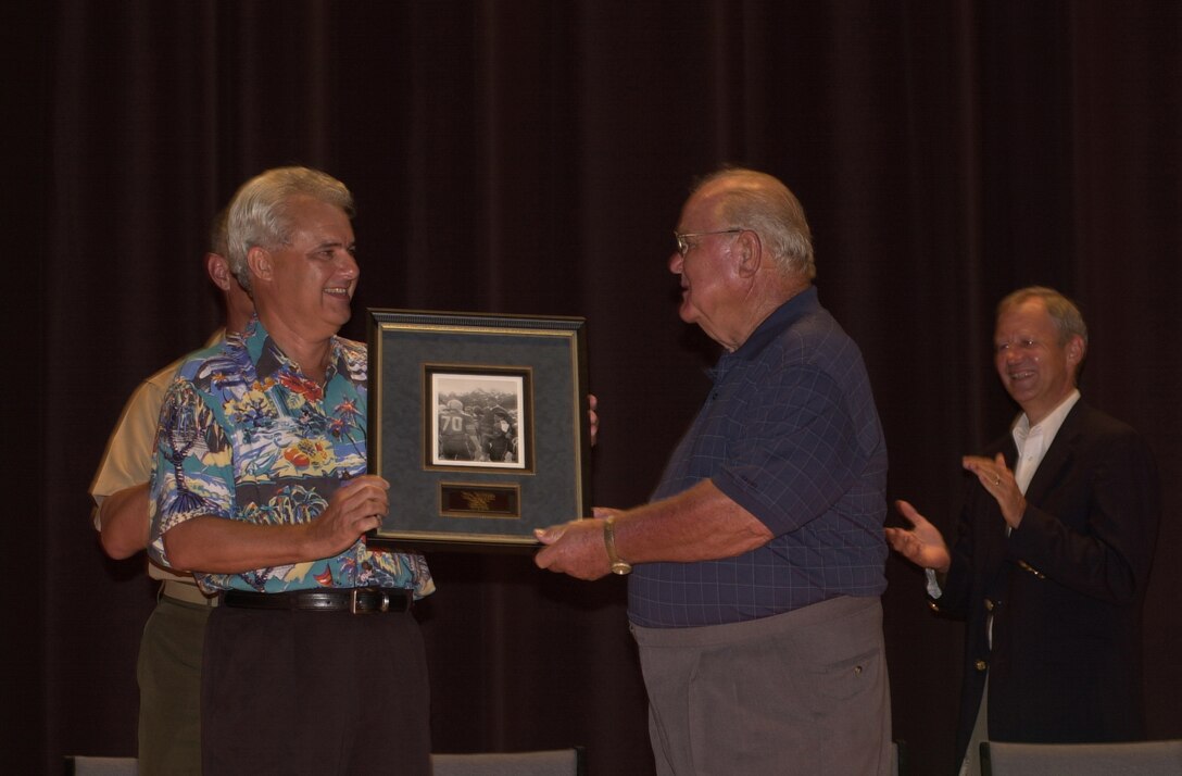 MARINE CORPS BASE CAMP LEJEUNE, N.C. - Bill Pearson presents Tom McGee with a picture of him after winning a high school home coming game here June 2. McGee was awarded the order of the Long Leaf Pine Award along with several other awards for his lasting contributions to the community in North Carolina. (Official U.S. Marine Corps photo by Lance Cpl. Brandon R. Holgersen)