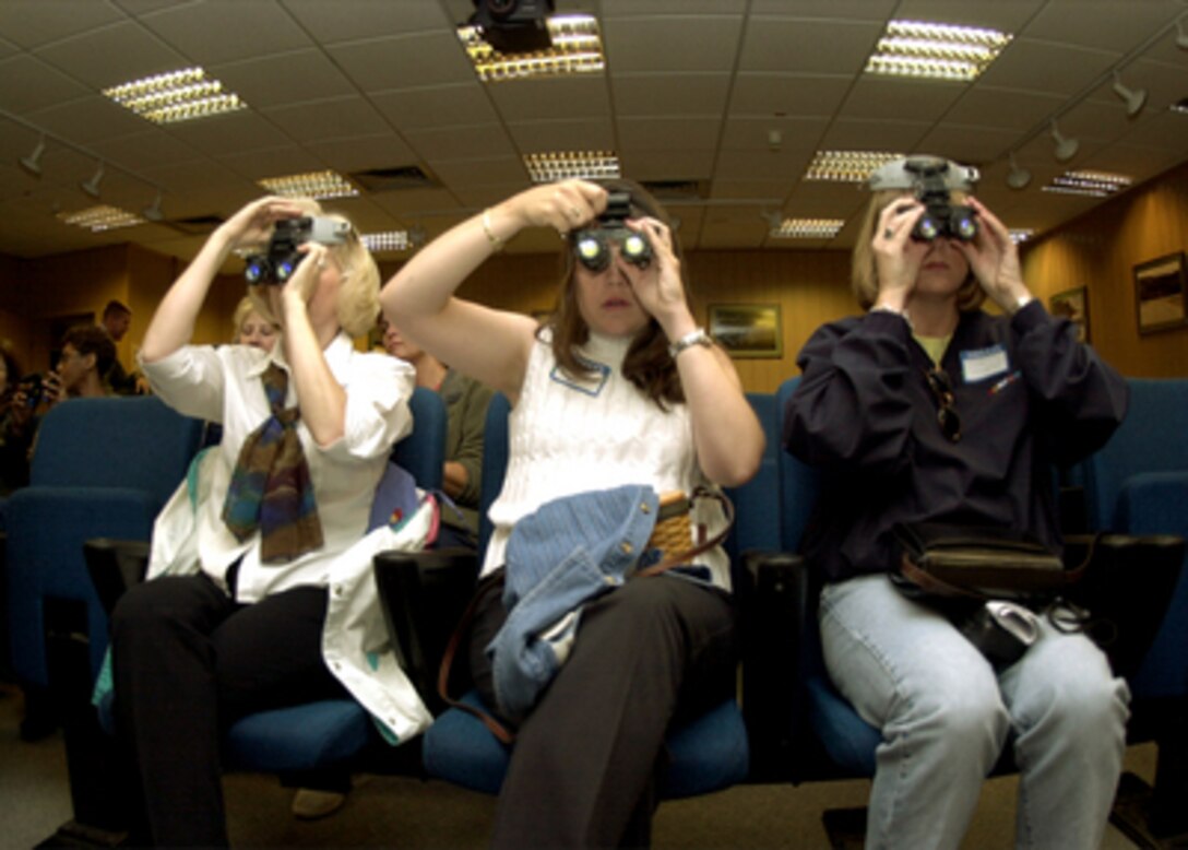 Marcie Todaro (left), Kellie Hill (center) and Kim Helgeson learn how to use a pair of night vision goggles during a spouse's orientation day at the 37th Airlift Squadron, 86th Air Lift Wing at Ramstein Air Base, Germany, on Aug. 11, 2001. The orientation is designed to acquaint spouses with some of the equipment and procedures their service member uses. 