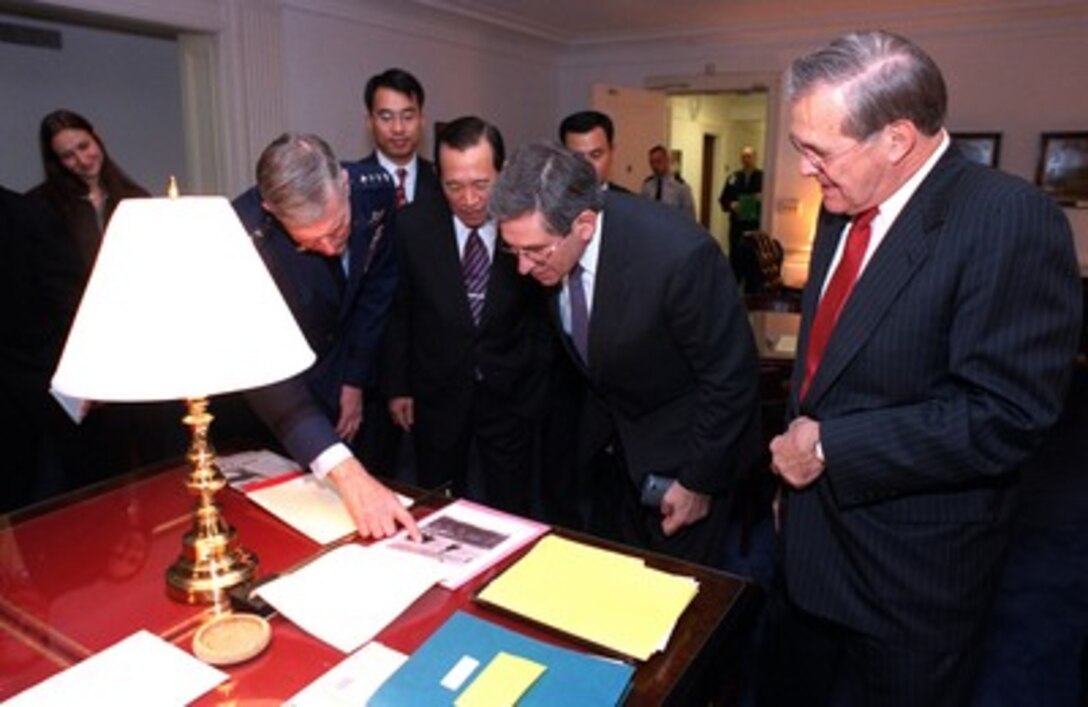 Secretary of Defense Donald H. Rumsfeld (right) shows his guests a photo of U.S. special operations troops riding horses in Afghanistan in his Pentagon office on Nov. 15, 2001. Gathered around the desk are from left to right Chairman of the Joint Chiefs of Staff Gen. Richard B. Myers, U.S. Air Force, South Korean Minister of National Defense Kim Dong Shin and Deputy Secretary of Defense Paul Wolfowitz. Rumsfeld hosted the defense leaders for in an evening reception following the annual, day-long, U.S.--Republic of Korea Security Consultative Meeting which provides an opportunity for the two nations to review their security relationships and propose modifications, as necessary, to deal with changing world conditions. 