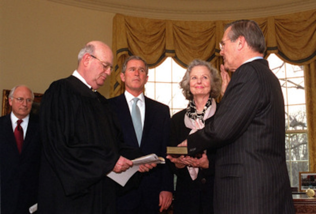 President George W. Bush and Vice President Dick Cheney watch as Donald H. Rumsfeld (right) is administered the oath of office as the 21st secretary of Defense by Judge Larry Silverman (left), while Joyce Rumsfeld holds the Bible in a ceremony at the White House Oval Office on Jan. 26, 2001. 