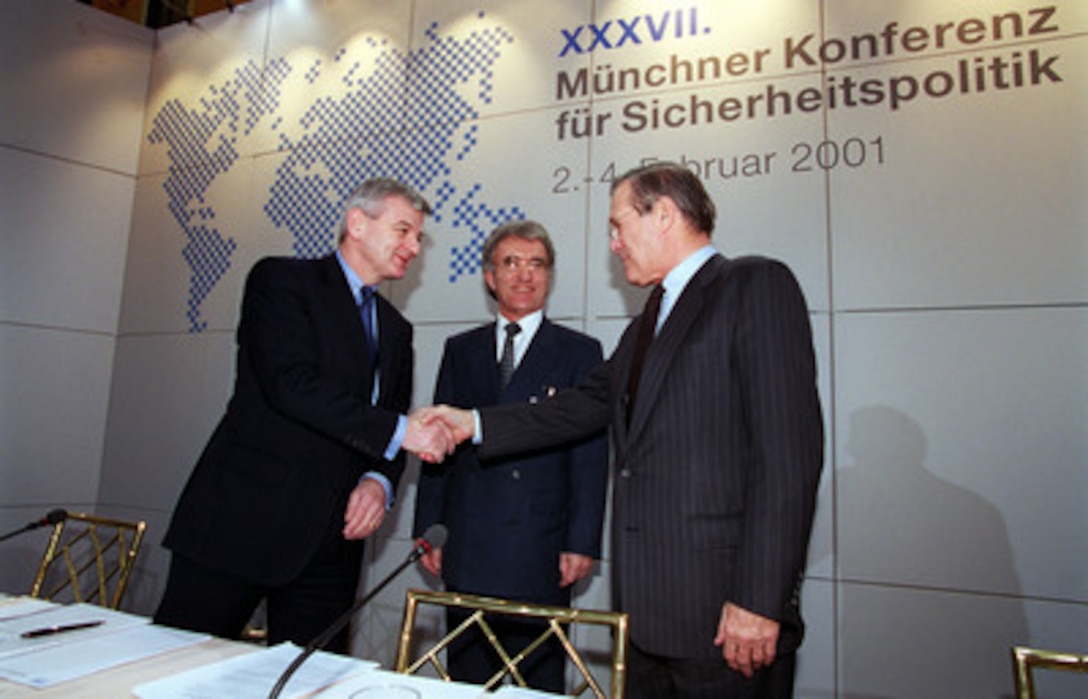Secretary of Defense Donald H. Rumsfeld (right) greets German Minister of Foreign Affairs Joschka Fischer (left) and Horst Teltschik on the dais at the 37th Munich Conference on Security Policy Feb. 3, 2001. 