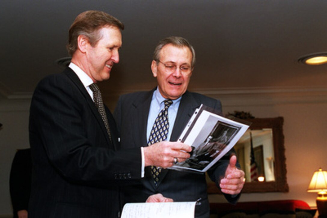 Secretary of Defense William S. Cohen (left) and Secretary of Defense-designate Donald H. Rumsfeld (right) look at old photographs as they meet in Cohen's Pentagon office for a working breakfast on Jan. 5, 2001. Cohen and Rumsfeld are meeting to discuss defense issues and the transition. The photographs are of Rumsfeld during his previous term as Defense secretary from Nov. 20. 1975 through Jan. 20, 1977. 