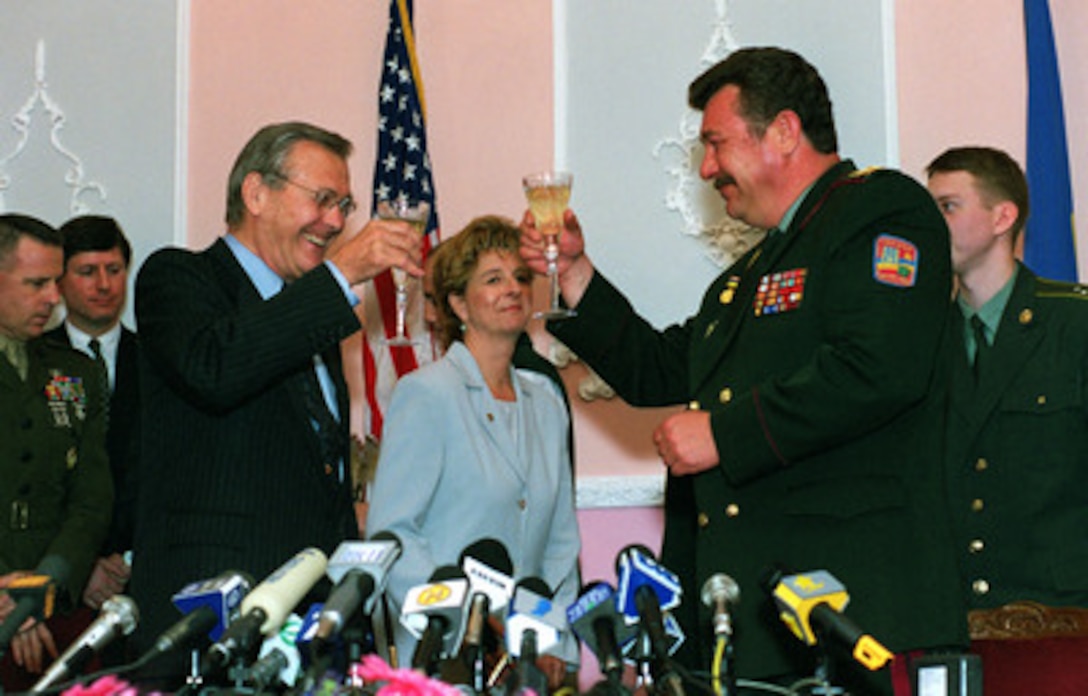Secretary of Defense Donald H. Rumsfeld (left) and Ukrainian Minister of Defense Gen. Oleksander Kuzmuk (right) celebrate with a toast following the ceremonial signing of a joint defense protocol agreement between the U.S. and Ukraine in Kiev, Ukraine, on June 5, 2001. Kiev is Rumsfeld's second stop on a seven-day, seven-nation, European tour. 