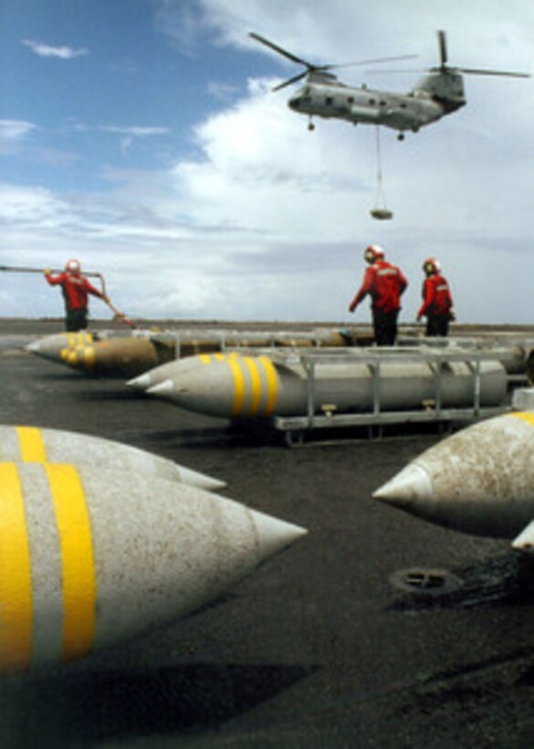 A Navy CH-46 Sea Knight helicopter delivers another pallet of bombs to the flight deck of the USS John F. Kennedy (CV 67) during an ammunition onload evolution with the USNS Mount Baker (T-AE 34) as the ships operate in the Atlantic Ocean on July 22, 2001. Red-shirted aviation ordnancemen will move the pallets of bombs from the flight deck to the ship's magazines below decks for storage. 