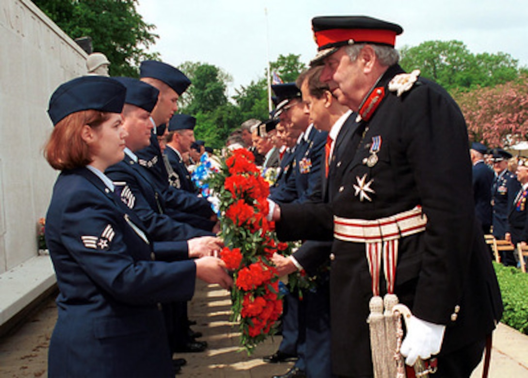 Senior Airman Rebecca A. Baucum (left) passes a wreath to Her Majesty's Lord Lieutenant of Cambridgeshire James Crowden during the Madingley Memorial Day Commemorative Service on May 28, 2001, at the Cambridge American Military Cemetery, Coton, Cambridge, England. This year marks the 57th annual memorial service honoring the American servicemen and women who are buried here and those listed on the Wall of the Missing. The cemetery was dedicated on July 16, 1956, as the only permanent American World War II cemetery in the British Isles. Baucum is attached to the 48th Communication Squadron, 48th Fighter Wing, RAF Lakenheath. 