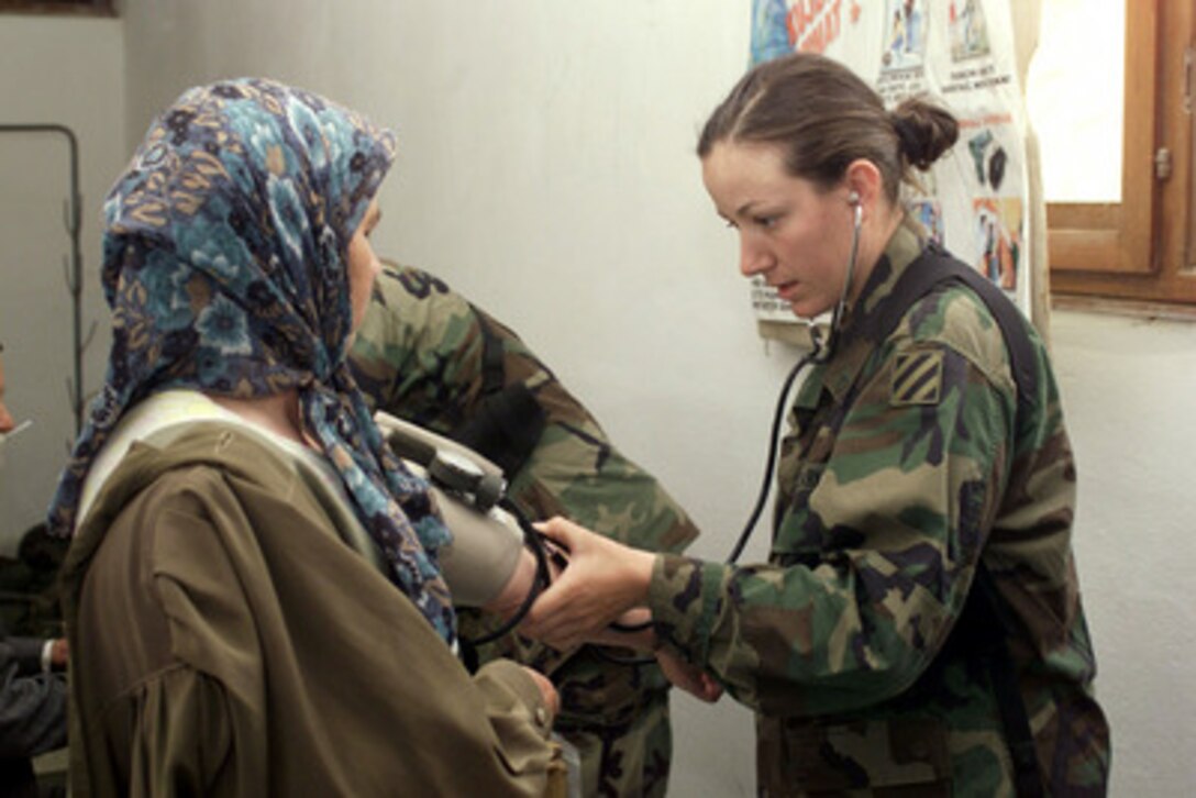 Army Pvt. Mary Anne Tillen measures a local woman's blood pressure during a Medical Civilian Assistance Program in a schoolhouse at Mucibaba, Kosovo, on May 31, 2001. Tillen is attached to HHC, 11th Engineer Battalion, 3rd Infantry Division, Fort Stewart, Ga., and is deployed to Kosovo in support of KFOR. KFOR is the NATO-led, international military force in Kosovo on the peacekeeping mission known as Operation Joint Guardian. 