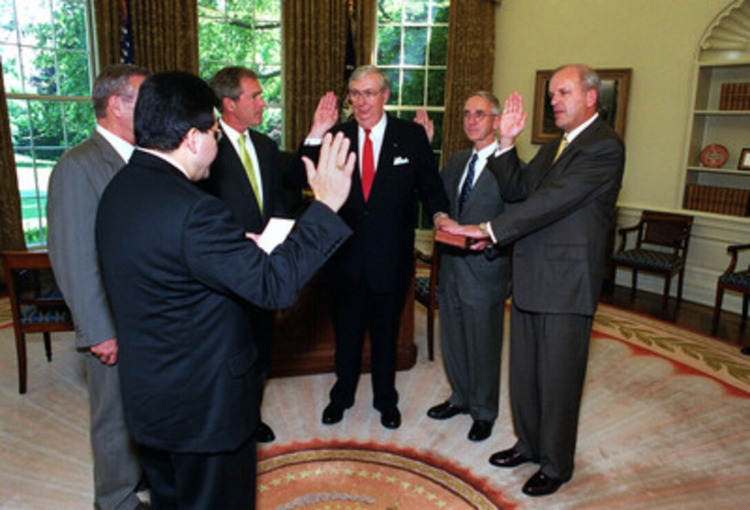 President George W. Bush (3rd from left) and Secretary of Defense Donald H. Rumsfeld (left, partially obscured) watch as Judge Alberto Gonzales (left foreground) administers the oath of office to (right to left) Secretary of the Army Thomas White, Secretary of the Navy Gordon England, and Secretary of the Air Force James Roche in the White House Oval Office on June 18, 2001. 