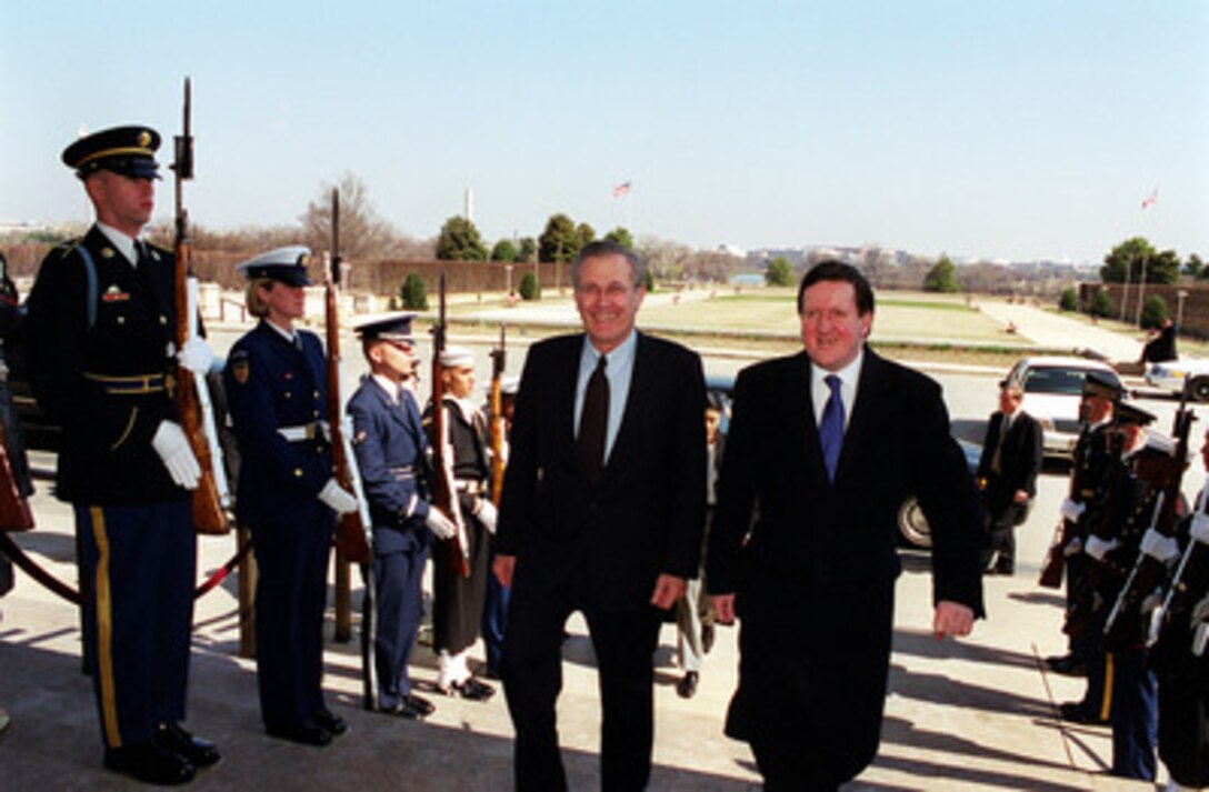 Secretary of Defense Donald H. Rumsfeld (left) escorts NATO Secretary General Lord George Robertson (right) through an honor cordon and into the Pentagon on March 8, 2001. 