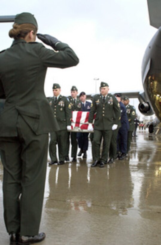 A soldier salutes a fallen comrade as U.S. Army and Air Force casket bearers carry the remains of one of six U.S. servicemen killed in a March 12 training exercise in Kuwait from a C-17 Globemaster III at Ramstein Air Base, Germany, on March 15, 2001. The remains will be transported to the Landstuhl Regional Medical center for identification. 