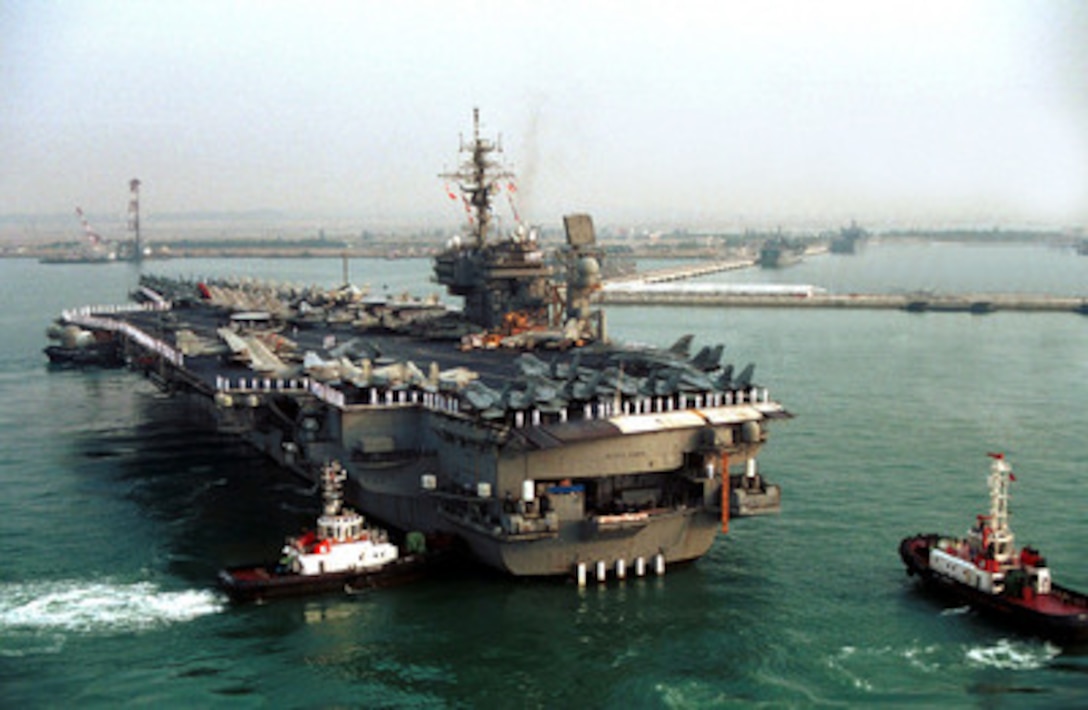 Tug boats push the USS Kitty Hawk (CV 63) towards Singapore's new deep-draft vessel pier at Changi Naval Base on March 22, 2001. The Kitty Hawk is the first U.S. aircraft carrier to moor at the pier which is one of the few piers in the Pacific that is large enough to berth a carrier and only one of two located in Southeast Asia. The aircraft carrier is in Singapore for a scheduled port visit during a routine deployment. 