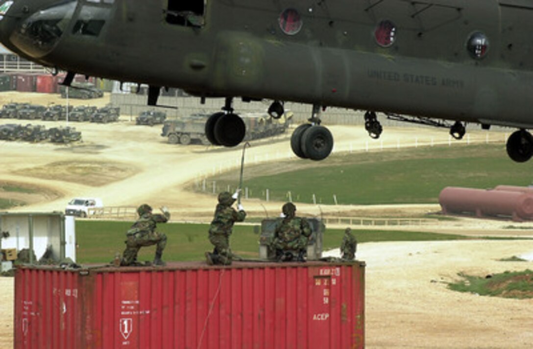 A U.S. Army soldier reaches up to touch a hovering CH-47 Chinook helicopter with a grounding rod as he and his fellow soldiers prepare to sling load a container from Camp Bondsteel, Kosovo, on March 13, 2001. The grounding rod is used to dissipate the build up of static electricity on the helicopter so the soldiers who attach the loading slings won't be shocked. The soldiers are from A Company Headquarters and Headquarters Detachment Task Force 47 and the Chinook is attached to the 501st Aviation Battalion. The container will be used to build a security outpost on a hilltop to support KFOR. KFOR is the NATO-led, international military force in Kosovo on the peacekeeping mission known as Operation Joint Guardian. 