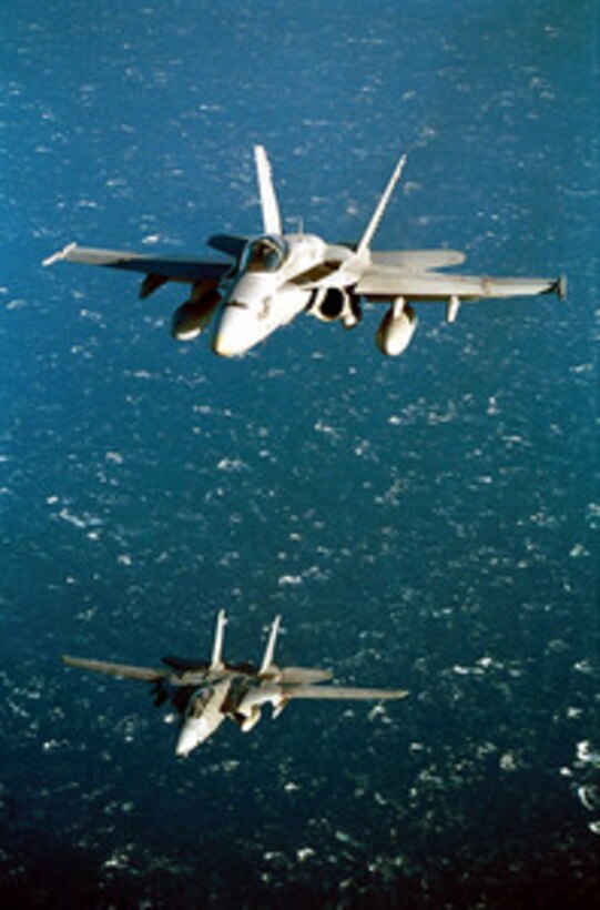 An F/A-18 Hornet (top) and an F-14 Tomcat conduct routine flight operations over the Sea of Japan on March 8, 2001. The two aircraft are operating from the flight deck of the aircraft carrier USS Kitty Hawk (CV 63). The Hornet is attached to Strike Fighter Squadron 27 and the Tomcat is attached to Fighter Squadron 154, both of Atsugi Naval Air Facility, Japan. 
