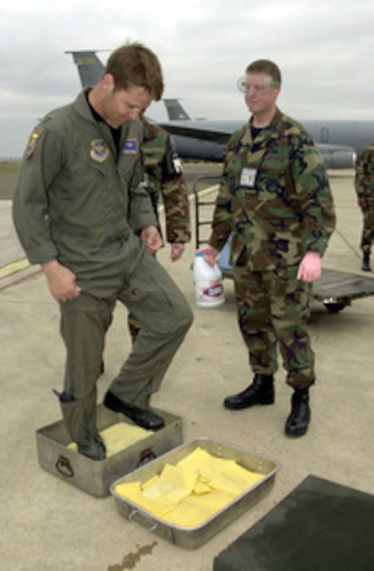 Air Force Capt. Tommy Howard (left) steps into pans of bleach on the tarmac at Istres, France, to disinfect his shoes before flying back to the United States on April 25, 2001. Personnel deployed here must sanitize their shoes and military cargo is also being sanitized to prevent the possible spreading of Foot and Mouth Disease stateside. Howard is a KC-135 Stratotanker pilot with the Alabama Air National Guard's 117th Air Refueling Wing, Birmingham, Ala. 