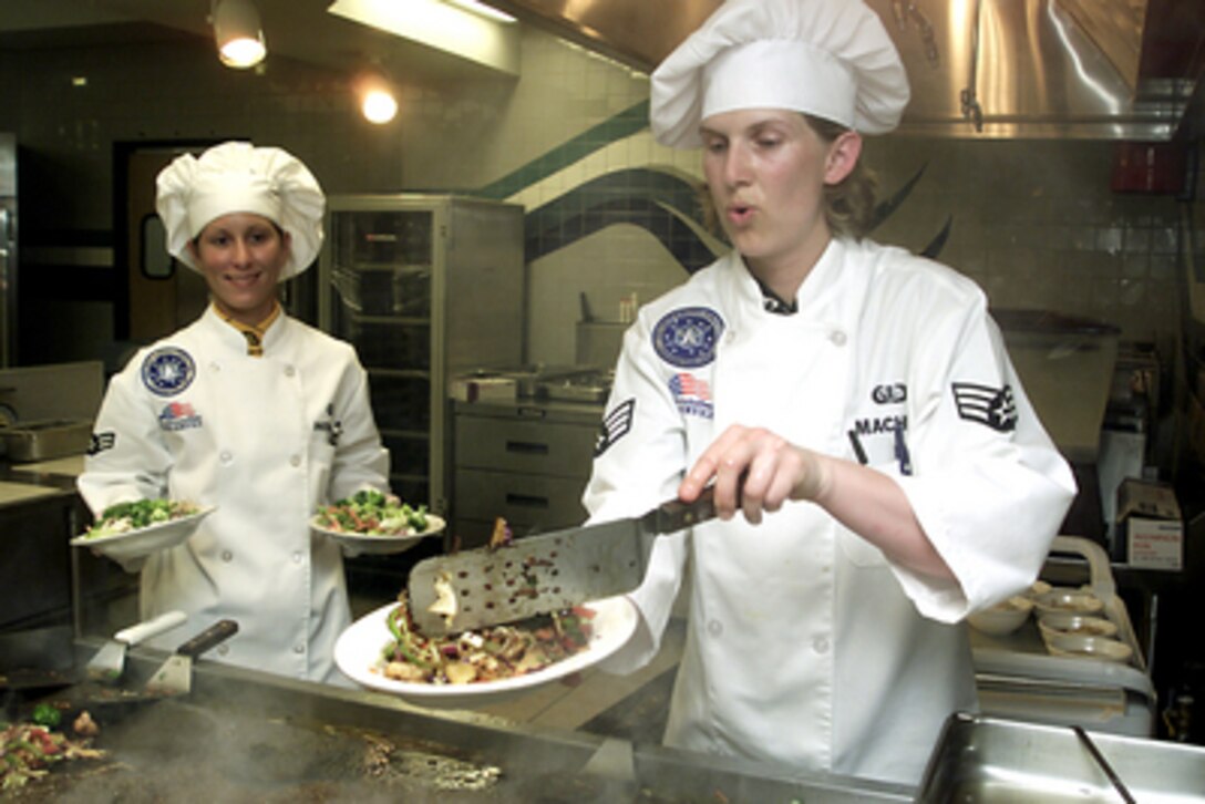 Senior Airman Marilyn Machay (right) prepares a plate of Mongolian stir fry as she and fellow Chef Airman 1st Class Deanna Howell are evaluated during the Chef's Competition of Exercise Guardian Challenge on May 7, 2001. Guardian Challenge is a four-day competition hosted annually at Vandenberg Air Force Base, Calif., to test the wartime readiness of Air Force Space Command's finest professionals. Machay and Howell are attached to the 90th Space Wing. 