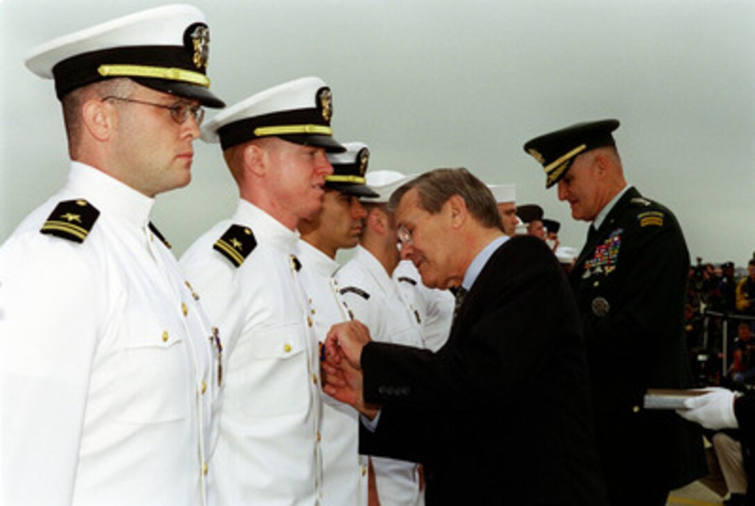 Secretary of Defense Donald H. Rumsfeld adjusts the medal of Lt. j.g. Jeffrey Vignery of Goodland, Kansas, during an award ceremony May 18, 2001. Chairman, Joint Chiefs of Staff Henry H. Shelton (right) is presenting the awards to the 24 members of the U.S. Navy EP-3 crew who were forced to make an emergency landing April 1, 2001, on Hanian Island, Peoples Republic of China. Thousands of spectators attending the opening ceremony of the Joint Services Open House at Andrews Air Force Base, MD witnessed the event. 