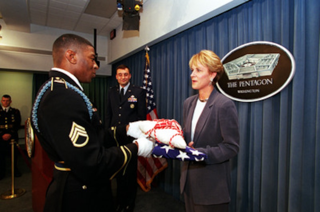 SSG Jake Johnson, USA, deputy director for pentagon tours, presents the official flag of the assistant secretary of defense to Ms. Victoria Clarke after she was sworn in as ASD for public affairs on May 22, 2001. 