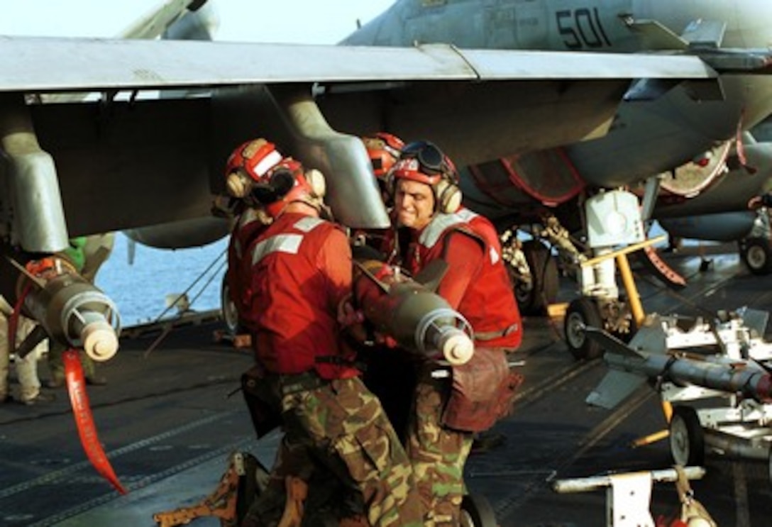 Aviation ordnancemen on the USS Enterprise (CVN 65) muscle ordnance into place as aircraft are readied for strike missions against al Qaeda terrorist training camps and military installations of the Taliban regime in Afghanistan on Oct. 7, 2001, during Operation Enduring Freedom. The carefully targeted actions are designed to disrupt the use of Afghanistan as a base for terrorist operations and to attack the military capability of the Taliban regime. 