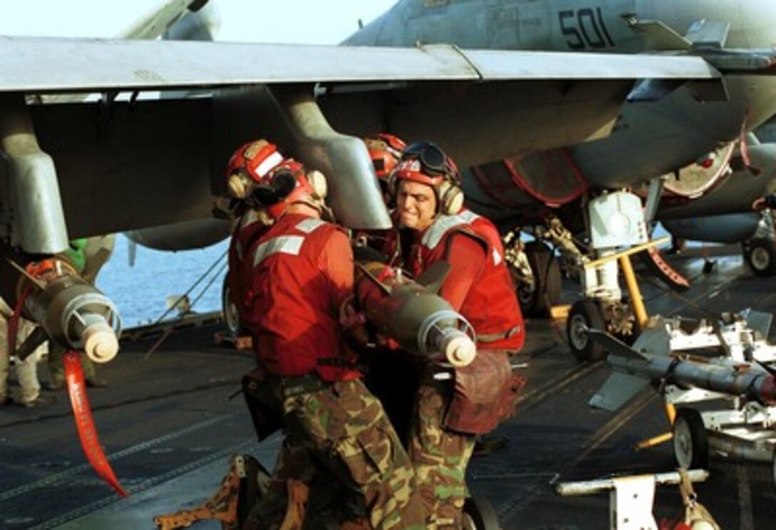 Aviation ordnancemen on the USS Enterprise (CVN 65) muscle ordnance into place as aircraft are readied for strike missions against al Qaeda terrorist training camps and military installations of the Taliban regime in Afghanistan on Oct. 7, 2001, during Operation Enduring Freedom. The carefully targeted actions are designed to disrupt the use of Afghanistan as a base for terrorist operations and to attack the military capability of the Taliban regime. 