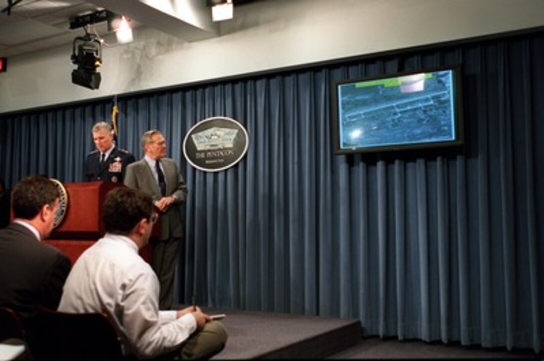 Chairman of the Joint Chiefs of Staff Gen. Richard B. Myers, U.S. Air Force, reports on the bombing of the Shindand Airfield in Afghanistan, as Secretary of Defense Donald H. Rumsfeld looks at the battle damage assessment photograph during a Pentagon press briefing on Oct. 9, 2001. Myers and Rumsfeld reported on the bombing of targets in Afghanistan and the progress of Operation Enduring Freedom. 