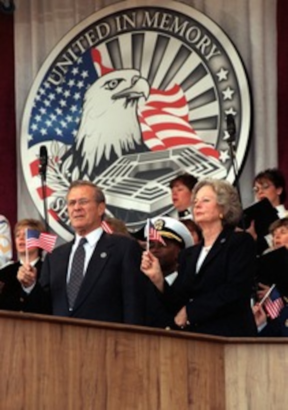 Secretary of Defense Donald H. Rumsfeld and his wife Joyce wave the flag as the choir sings "God Bless America" during a memorial service at the Pentagon on Oct. 11, 2001, in honor of those who perished in the terrorist attack on the building. President George W. Bush, Rumsfeld and Chairman of the Joint Chiefs of Staff Gen. Richard B. Myers, U.S. Air Force, eulogized the 184 persons killed when a terrorist hijacked airliner was purposely crashed into the southwest face of the building on Sept. 11, 2001. 