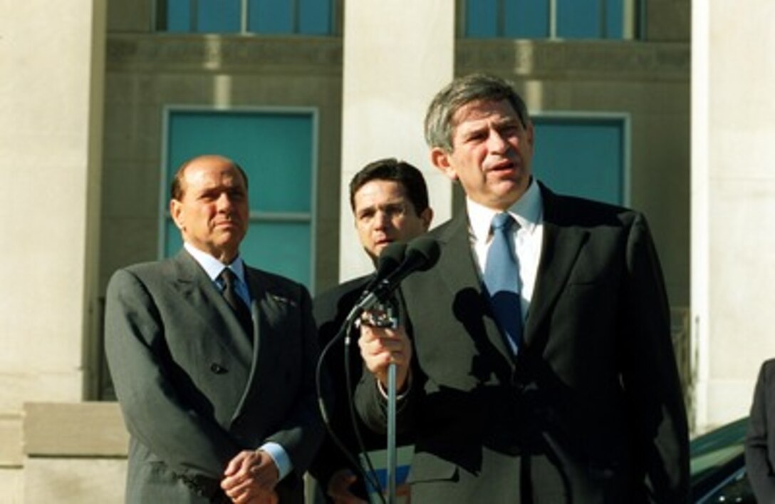 Italian Prime Minister Silvio Berlusconi (left) listens to his interpreter as Deputy Secretary of Defense Paul Wolfowitz (right) responds to a reporter's question during joint press availability at the Pentagon on Oct. 15, 2001. 
