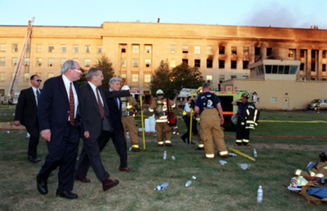 Secretary of Defense Donald H. Rumsfeld (center) leads Sen. Carl Levin (left), D-Mich., and Sen. John Warner (right), R-Va., to the crash scene at the Pentagon heliport on Sept. 11, 2001. Rumsfeld earlier conducted a news conference with reporters in the Pentagon briefing room on the terrorist attack of the Pentagon. 