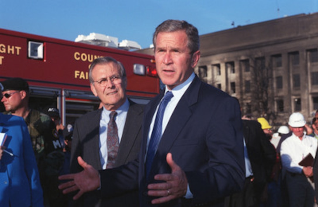 President George W. Bush (right) talks with reporters in front of the crash site at the Pentagon on Sept. 12, 2001. Secretary of Defense Donald H. Rumsfeld (left) guided Bush on a tour of the site. Bush and Rumsfeld thanked many of the fire fighters, police officers, search and rescue personnel, FBI investigators, and other professionals at the disaster site. 