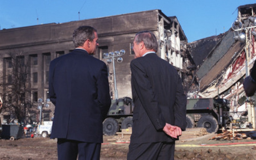 President George W. Bush (left), and by Secretary of Defense Donald H. Rumsfeld (right) look over the scene of destruction at the Pentagon on Sept. 12, 2001. On the morning of Sept. 11, an American Airlines flight was hijacked and deliberately crashed into the headquarters of the Department of Defense. The mid-portion of the western face of the Pentagon took the full brunt of the passenger jet. 