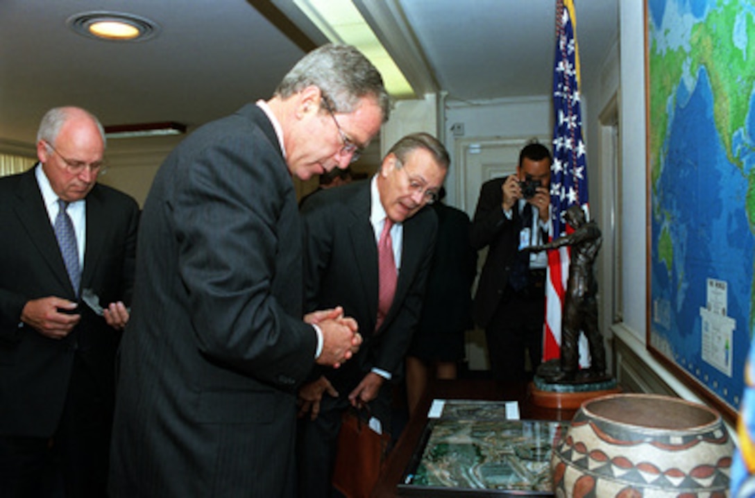 President George W. Bush (center) and Secretary of Defense Donald H. Rumsfeld (right) look at satellite images of the Pentagon before and after the Sept. 11 terrorist attack. Bush and Vice President Dick Cheney (left) met with Rumsfeld and other members of the national security team at the Pentagon on Sept. 17, 2001. Bush later informally greeted and thanked Pentagon personnel in the hallways and cafeteria. 