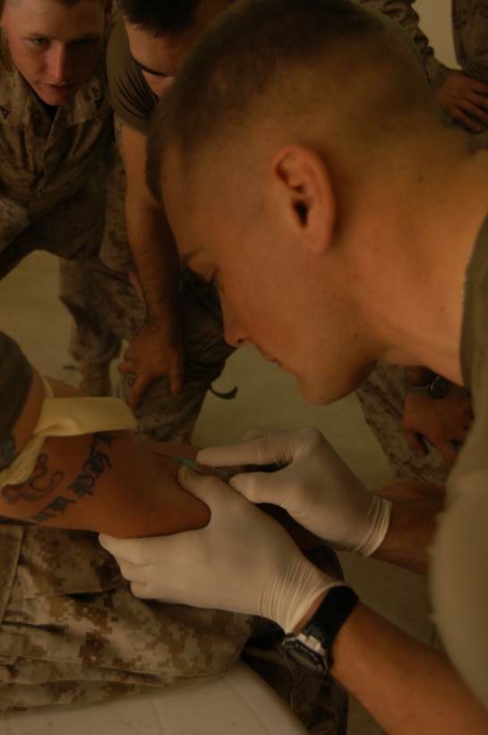 AL ASAD, Iraq--Cpl. Roy J. Lackey, 21, from Charleston, S.C., puts his knowledge to the test as he inserts an IV needle into a fellow Marine.  This training is necessary in the event a corpsman is tending to other patients in a combat situation.   Close to 30 sailors make up the Marine Wing Support Squadrons 271 medical unit providing care for more than 1,200 Marines and sailors here.  They utilize radiography equipment and have the ability to perform laboratory tests, issue medications, and provide the majority of preventive medicine for the forward operating bases of the 2nd Marine Aircraft Wing.