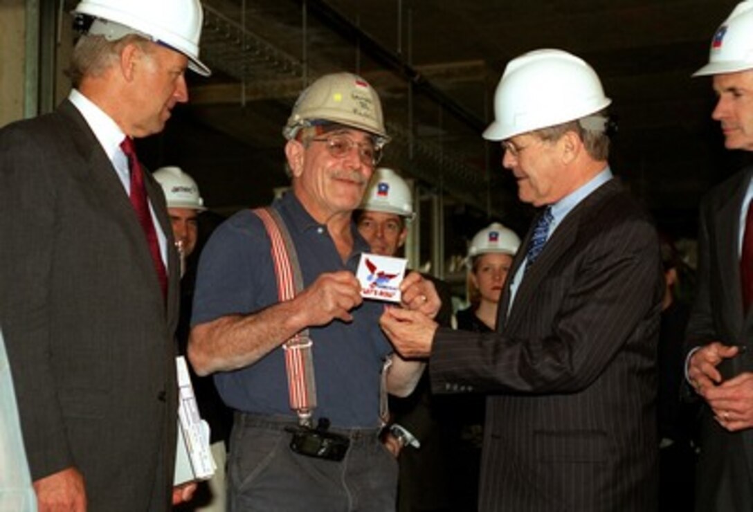 Secretary of Defense Donald H. Rumsfeld (2nd from right) presents a decal with the Project Phoenix "Let's Roll" logo to sheet metal worker Michael Flocco (2nd from left) at the Pentagon on April 10, 2002. Flocco, whose son was killed in the Sept. 11th terrorist attack on the Pentagon, received permission from his union in Delaware to work on the Pentagon reconstruction effort known as Project Phoenix. Delaware Senators Joseph Biden (left) and Thomas Carper (right) joined Rumsfeld in recognizing Flocco. 