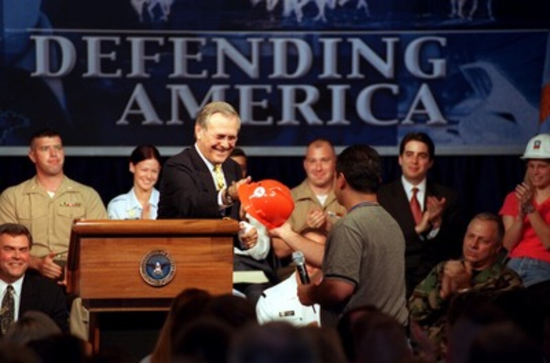Secretary of Defense Donald H. Rumsfeld returns a hard hat to John Trujillo after autographing it during a town hall meeting in the Pentagon on Aug. 6, 2002. Rumsfeld told the audience of the need for transformation in the Department of Defense. The meeting provides an opportunity for the Pentagon's military and civilian employees to ask questions of the secretary. Trujillo, a member of the Pentagon Renovation Program's Information Management and Telecommunications Team, asked Rumsfeld if he would autograph his hard hat. 