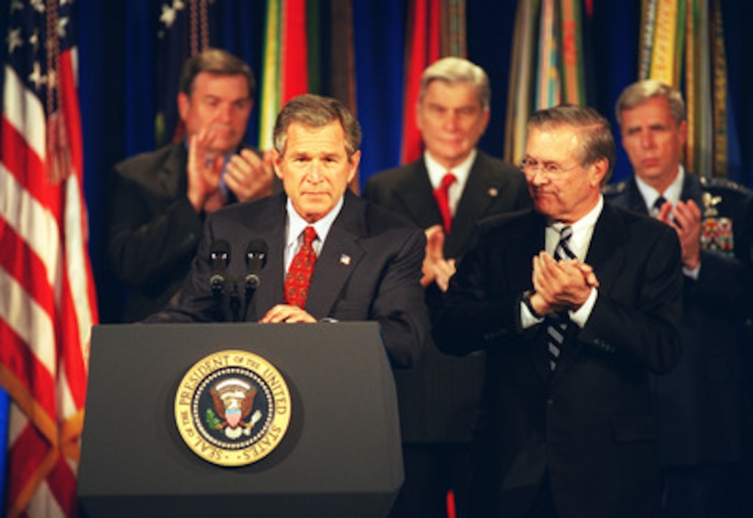 President George W. Bush addresses military and DoD civilian personnel at the Pentagon on Dec. 2, 2002. Bush was at the Pentagon to sign the Department of Defense Authorization Bill. Applauding the president's remarks are (left to right): Congressman Duncan Hunter, Senator John Warner, Secretary of Defense Donald H. Rumsfeld and Air Force Vice Chief of Staff Gen. Robert H. Foglesong. 
