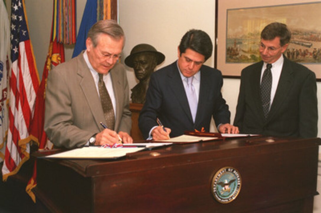 Secretary of Defense Donald H. Rumsfeld (left) and Spanish Minister of Defense Federico Trillo (center) sign documents formalizing a range of military-to-military cooperation programs between the two nations in the Pentagon on December 3, 2002. Standing at the right is Warren Hall of the office of the Department of Defense General Counsel. 