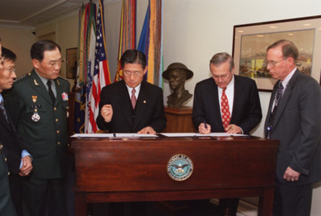 Secretary of Defense Donald H. Rumsfeld (2nd from right) and South Korean Minister of National Defense Lee Jun (3rd from right) sign documents formalizing a range of cooperative security programs between the two nations at the Pentagon on Dec. 5, 2002. Standing beside Minister Lee, is General Lee Nam-shin, South Korean Army, chairman of Republic of Korea Joint Chiefs of Staff. With Rumsfeld, at the right, is Warren Hall of the Department of Defense General Counsel Office. 